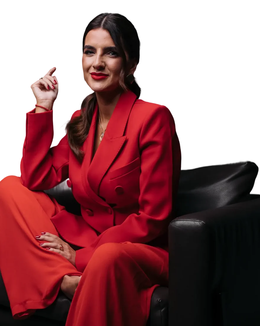 Ana Lisboa de terno vermelho, sentada numa poltrona preta, sorrindo